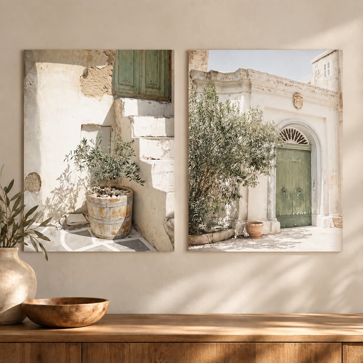 Two vertical canvas wall art prints depicting a sunlit Mediterranean courtyard with a green door, potted plants, and cream walls, displayed side by side on a beige wall above a wooden console with decorative vases.