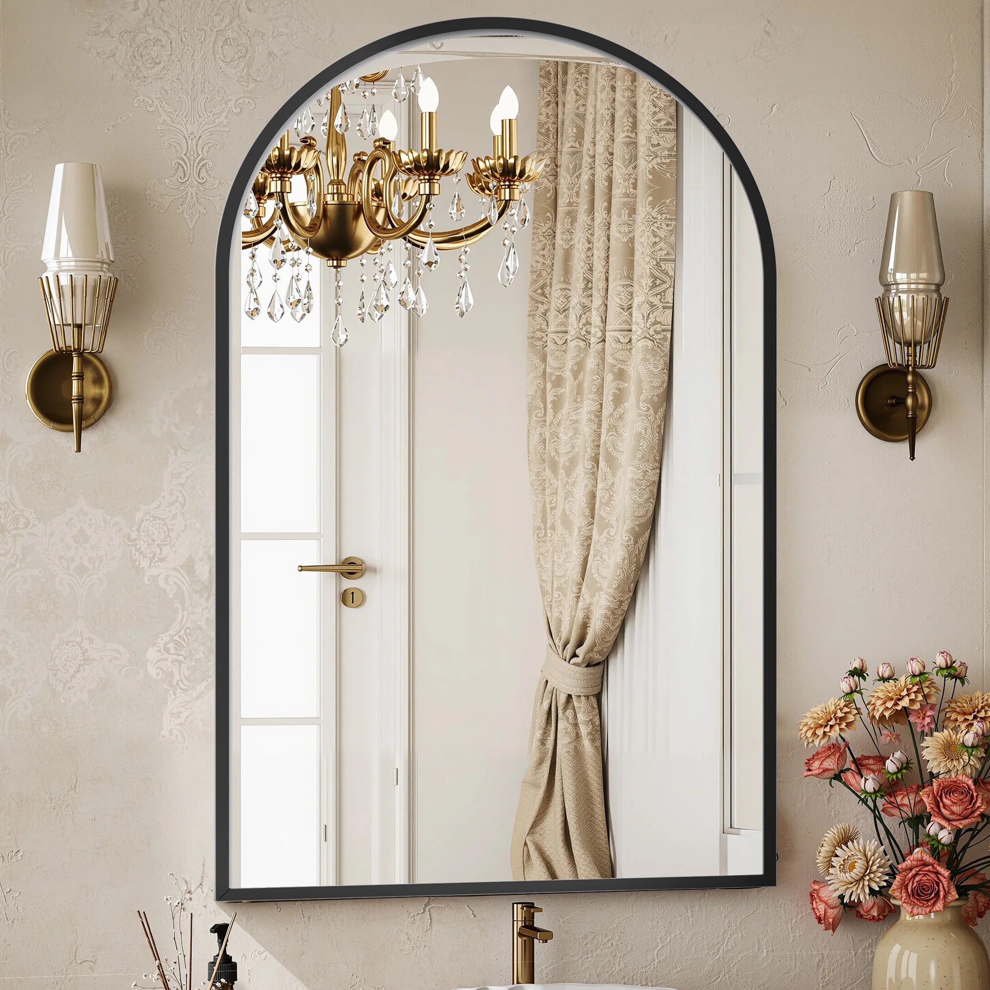Decorative mirror with a chandelier reflection, wall sconces, and floral arrangement.