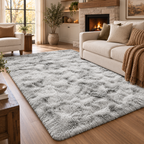 A large, plush shag area rug in a light gray and white mottled pattern, styled in a cozy, modern living room with a cream sofa, fireplace, and wooden floors.
