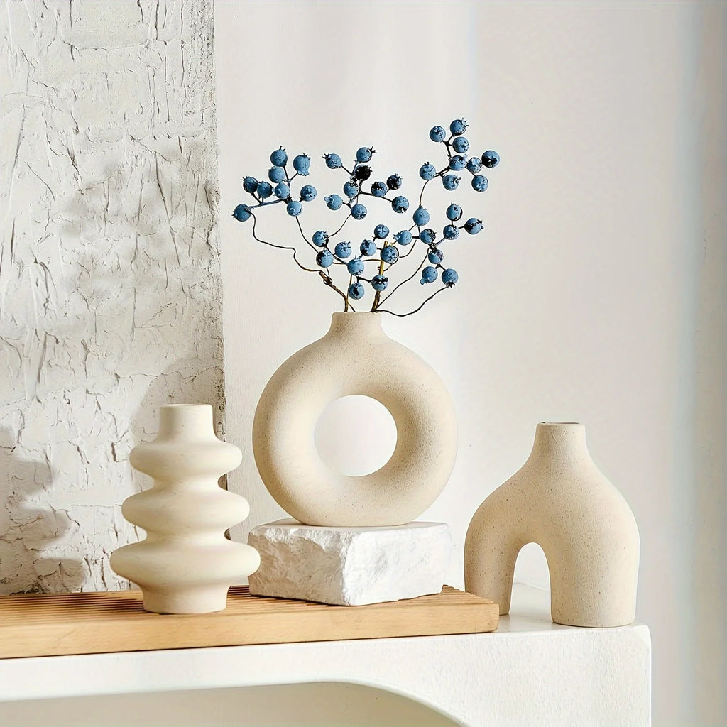 Three ceramic vases on a wooden shelf with a textured wall background