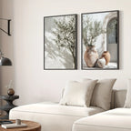 Two framed pictures of plants on a wall above a sofa in a living room.