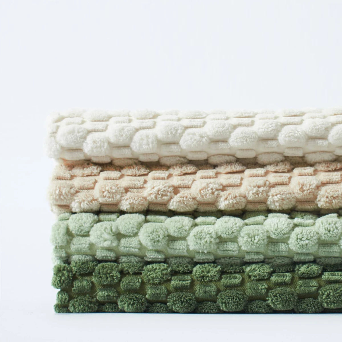 Stack of textured pillow covers in beige, pink, and green on a white background