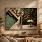 Two framed wall art prints hang on a beige wall above a wooden console. The left print shows an overhead poolside scene with lounge chairs, and the right print shows a tropical beach scene with palm trees, lounge chairs, and an umbrella.