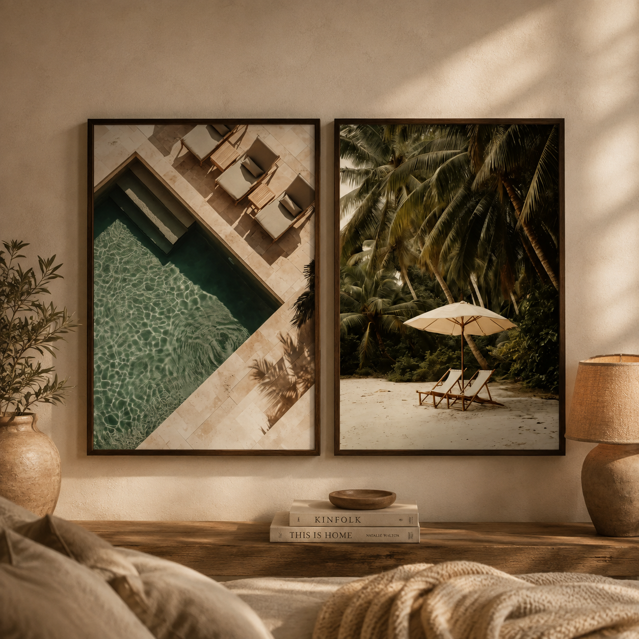 Two framed wall art prints hang on a beige wall above a wooden console. The left print shows an overhead poolside scene with lounge chairs, and the right print shows a tropical beach scene with palm trees, lounge chairs, and an umbrella.