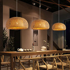 Three woven pendant lights hanging above a dining table with chairs in a modern interior setting.