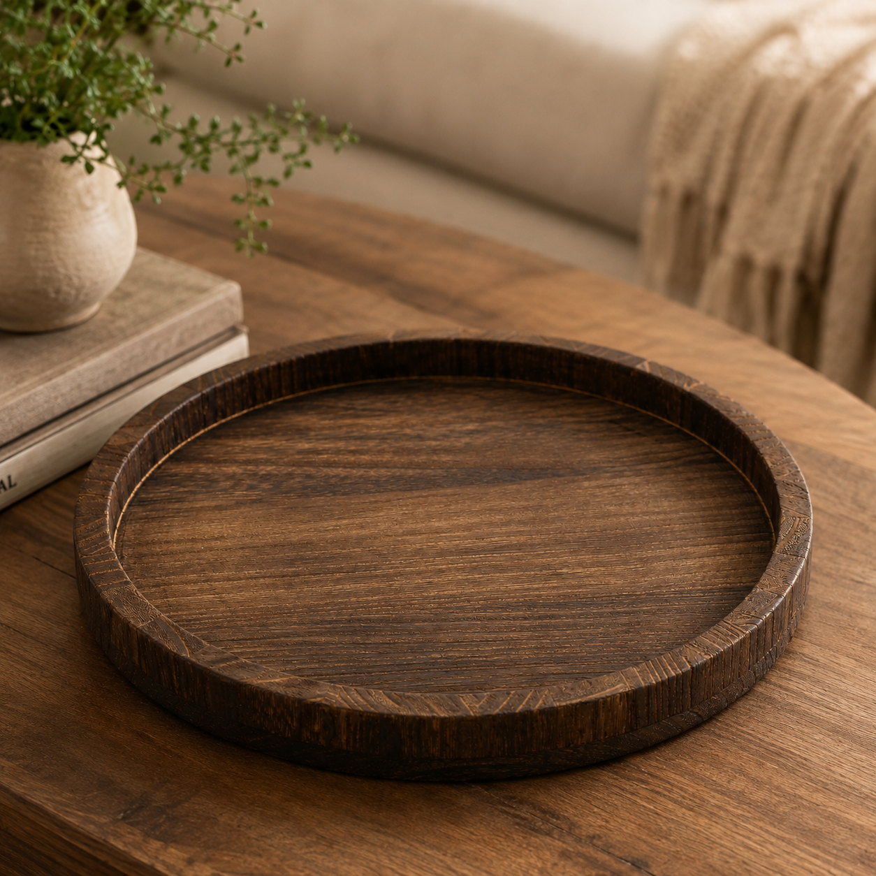 A round dark brown wooden serving tray with a raised rim, displayed on a matching wooden table in a cozy living room setting.