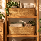 Two woven rectangular storage baskets on a wooden shelving unit, styled with folded blankets and potted plants in a warm, sunlit room.